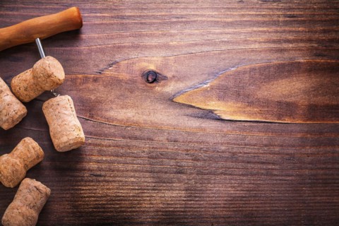Champagne corks and corkscrew on vintage wooden board with copyspace alcohol concept