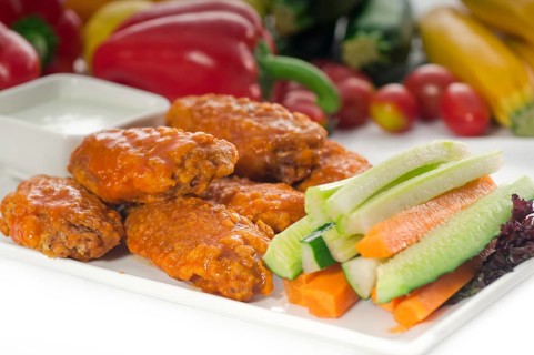 Classic buffalo chicken wings served with fresh pinzimonio and vegetables on background