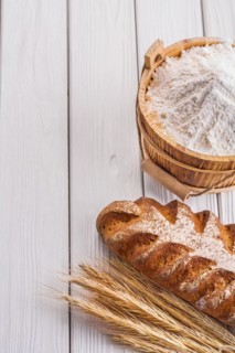 Loaf of bread Wheat ears Flour in wooden bucket on old white boards with copy space