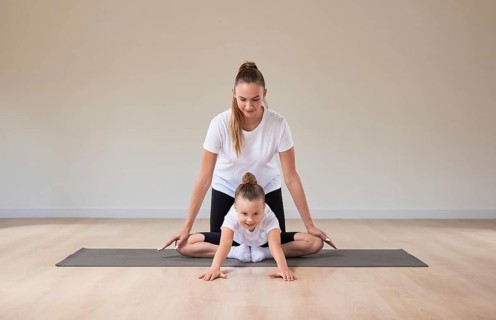 Beautiful female teacher helps a little girl stretch in a gymnastics class. The concept of education