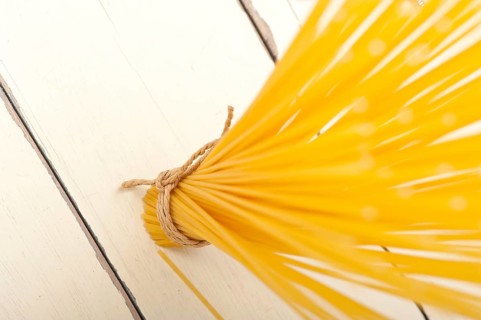 Italian pasta spaghetti tied with a rope on a rustic table