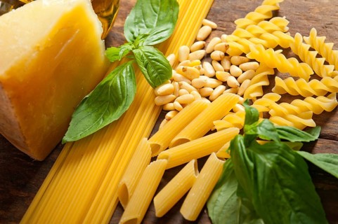 Italian basil pesto ingredients and raw pasta over old wood macro