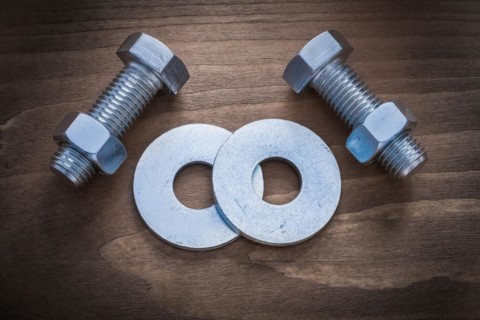 Bolt washers screwbolts and construction nuts on wooden background