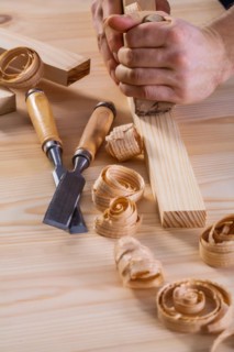 Close-up of a carpenter's hands with a plane and chisel