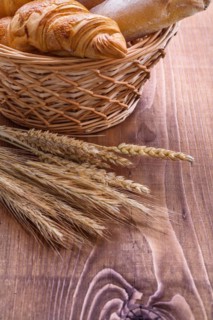 Croisants in a wicker basket and ears on an old wooden board
