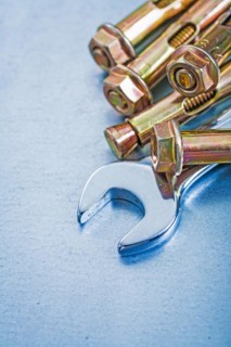 Metal anchor bolts for concrete walls and spanners on a metallic background Construction concept