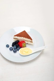 Classic Italian tiramisu dessert with berries and custartd pastry cream on side