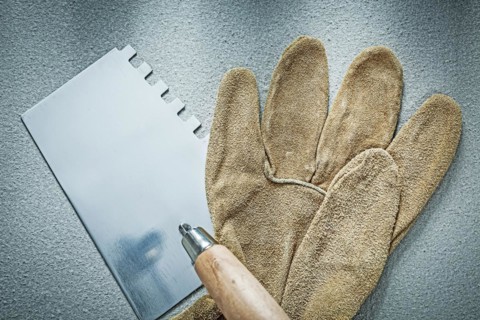 Bricklaying trowel working gloves on concrete background construction concept