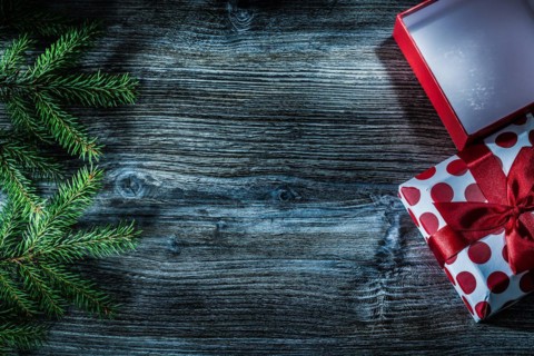 Wrapped present box fir branches on wooden board