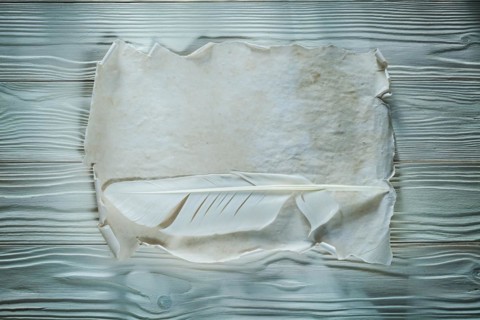 Quill vintage crumpled sheet of paper on wooden board