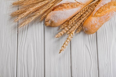 Baguettes and ears of wheat rye on vintage wooden painted boards food and drink concept