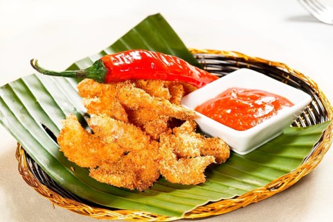 Fresh deep fried buffalo shrimps with a red chili pepper on top and sweet and sour sauce dip on side