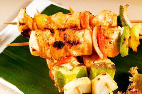Fresh chicken and vegetables skewers on a palm leaf thai style