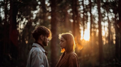 Beautiful fashionable couple in love in the forest at sunset in autumn