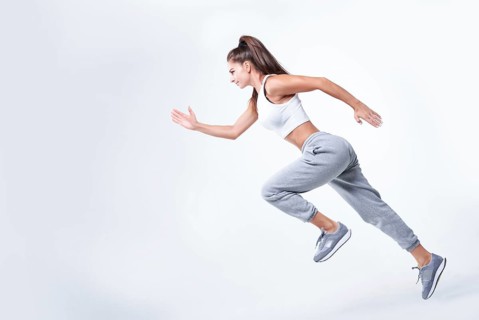 Sports woman runner on a white background. Photo of an attractive woman in fashionable sportswear. Dynamic movement. Side view. Sports and healthy lifestyle. Mixed media