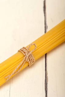 Italian pasta spaghetti tied with a rope on a rustic table