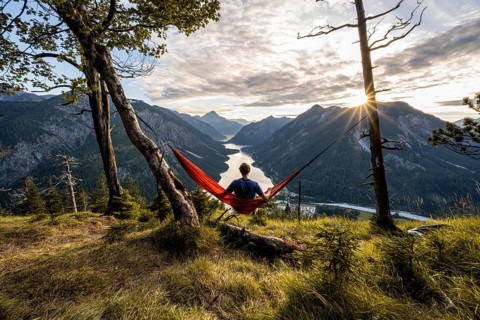 Young man sitting in an orange hammock