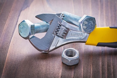 Adjustable spanner screws and nut on vintage wooden board Construction concept