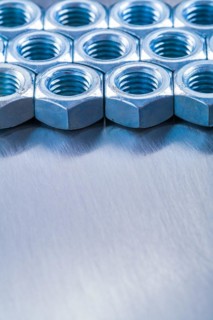 Copy space image of stainless steel nuts on metallic background construction concept