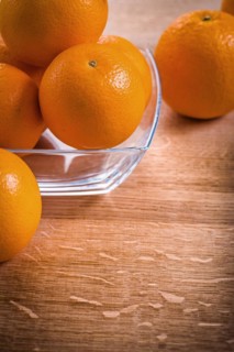 Orange fruit in a square glass bowl on a wooden table