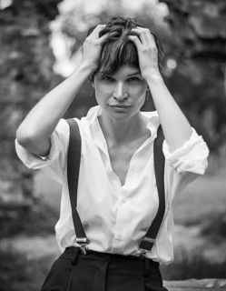 Image of a stylish beautiful woman in a park against the background of a destroyed building. The concept of style and fashion