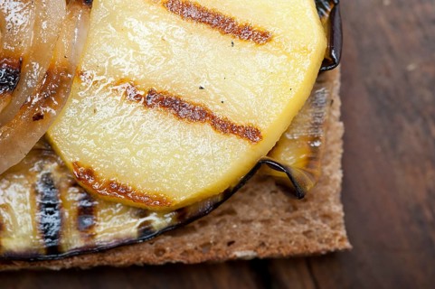 Grilled vegetables on rustic bread over wood table