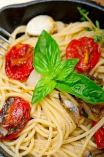 Italian spaghetti pasta with baked tomatoes basil and thyme sauce on a cast iron skillet