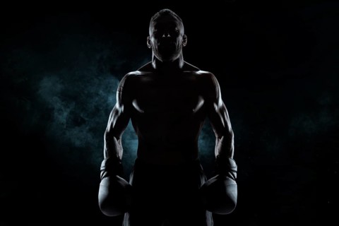 Kickboxer in black gloves posing on a background of smoke. The concept of mixed martial arts. MMA