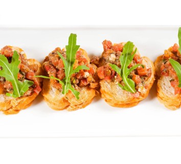 Fresh tipycal italian bruschetta with tomato and arugula on top