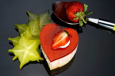 Heart shaped strawberry cake with carambola or star fruit decoration over black background