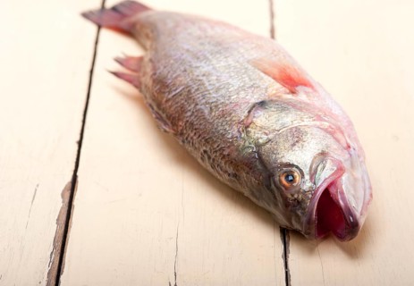 Fresh whole raw fish on a wooden table ready to cook