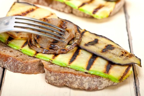 Grilled vegetables on rustic bread over wood table