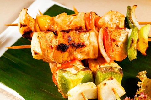 Fresh chicken and vegetables skewers on a palm leaf thai style