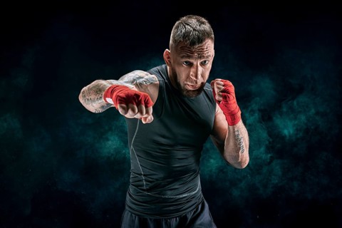Kickboxer in red bandages is boxing against a background of smoke. The concept of mixed martial arts. MMA