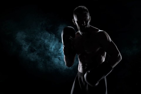 Kickboxer in black gloves posing on a background of smoke. The concept of mixed martial arts. MMA