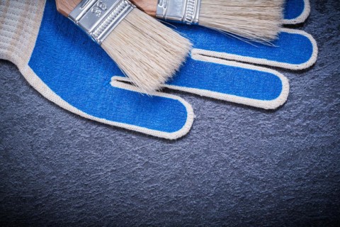 Paint brushes safety gloves on black surface construction concept