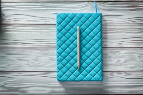 Blue leather soft notepad and classic wooden pencil on white vintage wooden boards