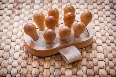 Single wooden massager with rubber band on wicker mat Healthcare concept