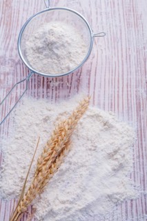 Ears of rice flour and sieve on an old wooden board