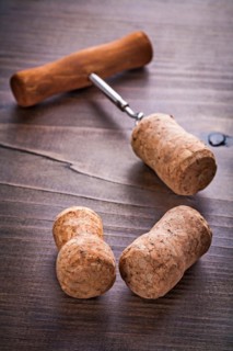 Champagne corks and corkscrew on vintage wooden board alcohol concept