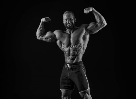 Silhouette of a strong bodybuilder. Confident young fitness athlete with a powerful body and perfect abs. Black and white photography. Dramatic light. Mixed media