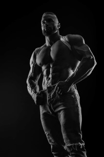 Silhouette of a strong bodybuilder. Confident young fitness athlete with a powerful body and perfect abs. Black and white photography. Dramatic light. Mixed media