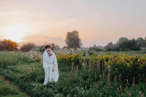 Loving couple of newlyweds at sunset in the field