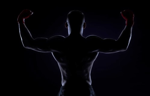 Kickboxer in red bandages raised his hands in victory. Back view. The concept of mixed martial arts. MMA