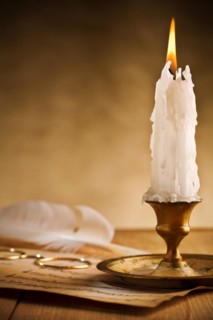 Antique brass candlestick with burning candle