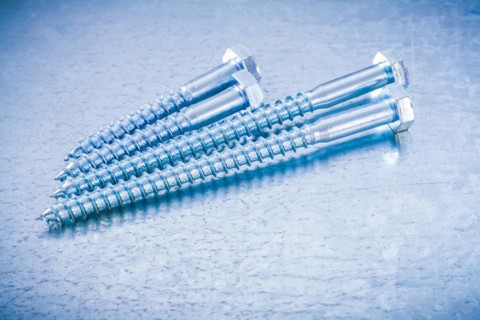 Composition of metal threaded bolts on a metallic background Design concept
