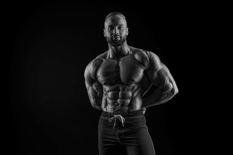 Silhouette of a strong bodybuilder. Confident young fitness athlete with a powerful body and perfect abs. Black and white photography. Dramatic light. Mixed media