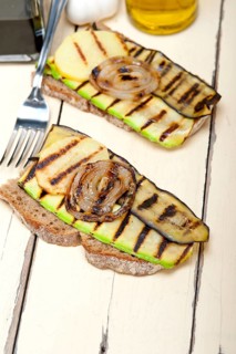 Grilled vegetables on rustic bread over wood table