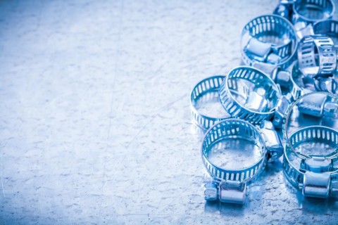Copy space image of stainless steel hollowed hose clamps on metallic background construction concept