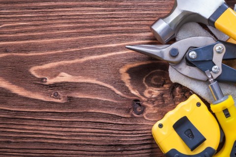 Hammer Protective glove Tape measure Screwdriver and pliers on wooden board